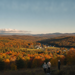 Bennington County weather forecast: three people overlook colorful autumn hills beneath a clear sky.