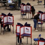 Voters cast ballots at separate voting booths, illustrating local safeguards a — federal interference in midterm elections