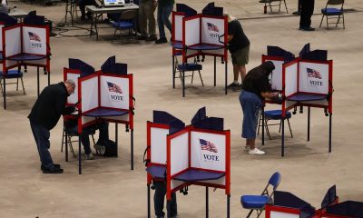 Voters cast ballots at separate voting booths, illustrating local safeguards a — federal interference in midterm elections