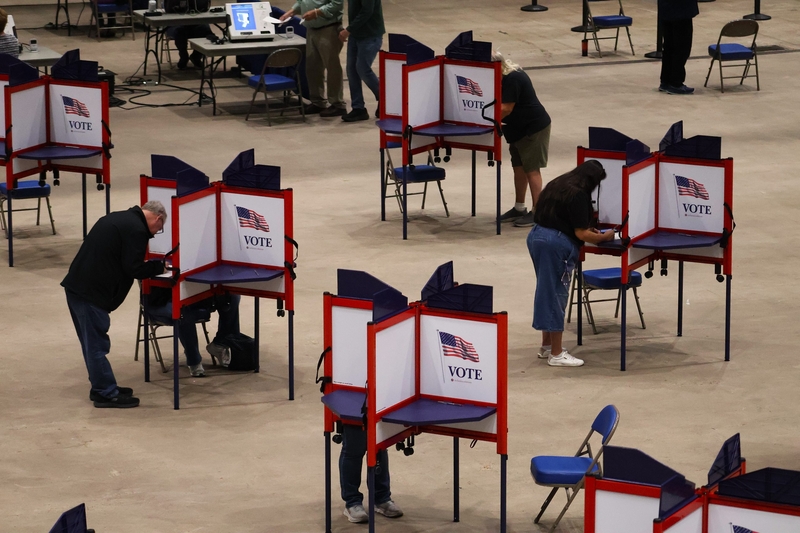 Voters cast ballots at separate voting booths, illustrating local safeguards a — federal interference in midterm elections