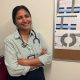 A smiling female doctor with a stethoscope stands with arms crossed in front of a bul — foreign doctors physician shortage