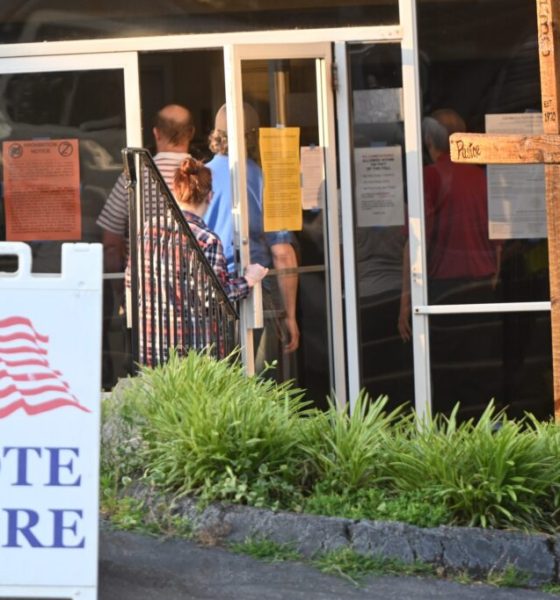 DOJ election monitors 2026 story: voters enter a polling place beside a “Vote Here” sign.