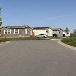 Manufactured homes line a quiet residential street beneath a clear b — 21st Century ROAD to Housing Act manufactured homes