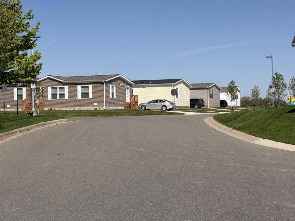 Manufactured homes line a quiet residential street beneath a clear b — 21st Century ROAD to Housing Act manufactured homes