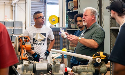 Workers gather around machinery in a workshop, illustrating the labor challenges affecting new home completions.