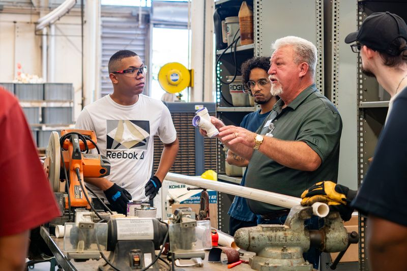 Workers gather around machinery in a workshop, illustrating the labor challenges affecting new home completions.