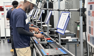 Workers operate equipment along an industrial production line, illustrating Vermont Job Losses and employment trends.