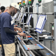 Workers operate equipment along an industrial production line, illustrating Vermont Job Losses and employment trends.