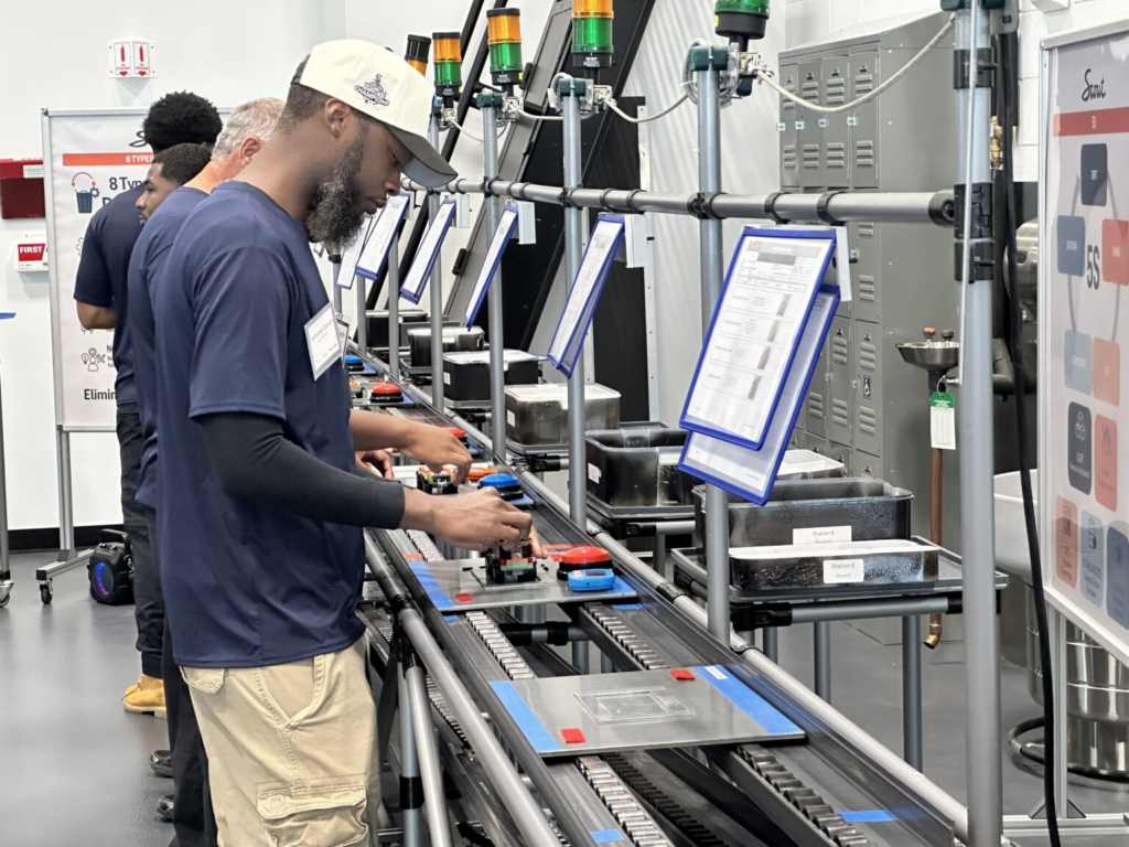 Workers operate equipment along an industrial production line, illustrating Vermont Job Losses and employment trends.