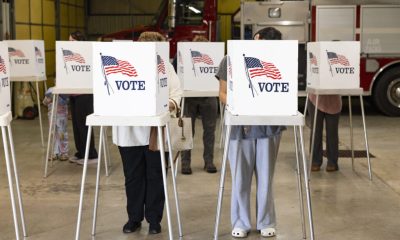 Trump DOJ election subpoenas story illustration: voters cast ballots at private voting booths marked with American flags.