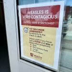 A sign warning about the contagious nature of measles, instructing people to wear masks and check — US measles cases 2025