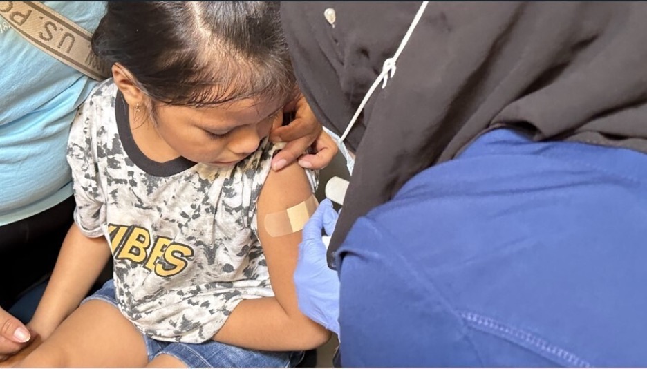 A young child receiving a vaccination in a healthcare setting, highlighting the New York measles emergency response.