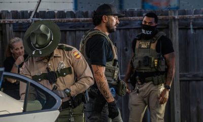 Law enforcement officers in tactical gear at a scene, highlighting — federal funding local police immigration enforcement
