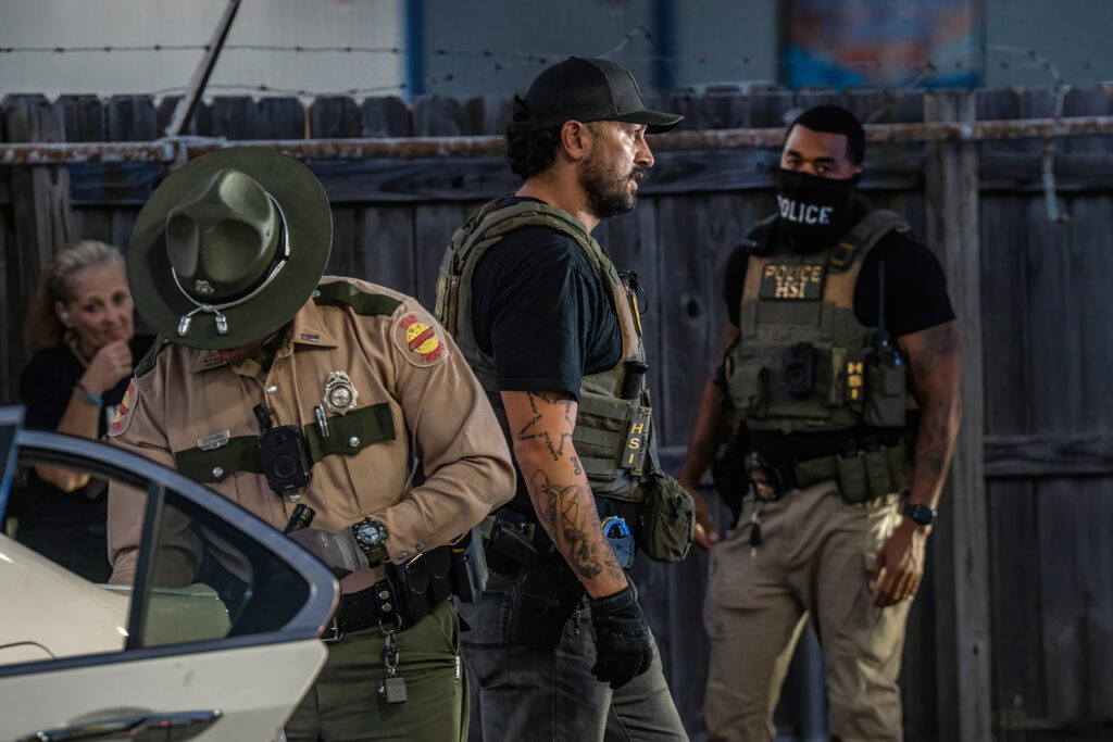 Law enforcement officers in tactical gear at a scene, highlighting — federal funding local police immigration enforcement