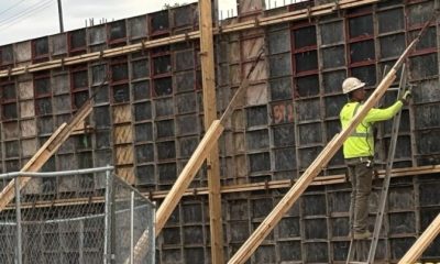 Construction worker in a bright yellow shirt working on a wooden framework at a constructi — skilled trade worker shortage