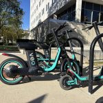 Parked electric scooters with turquoise accents beside a building, illustrating e-bike speed laws and regulations.