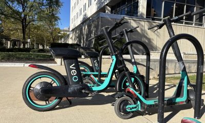 Parked electric scooters with turquoise accents beside a building, illustrating e-bike speed laws and regulations.