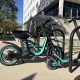 Parked electric scooters with turquoise accents beside a building, illustrating e-bike speed laws and regulations.