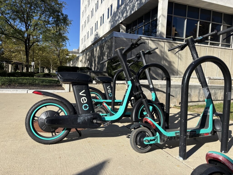 Parked electric scooters with turquoise accents beside a building, illustrating e-bike speed laws and regulations.