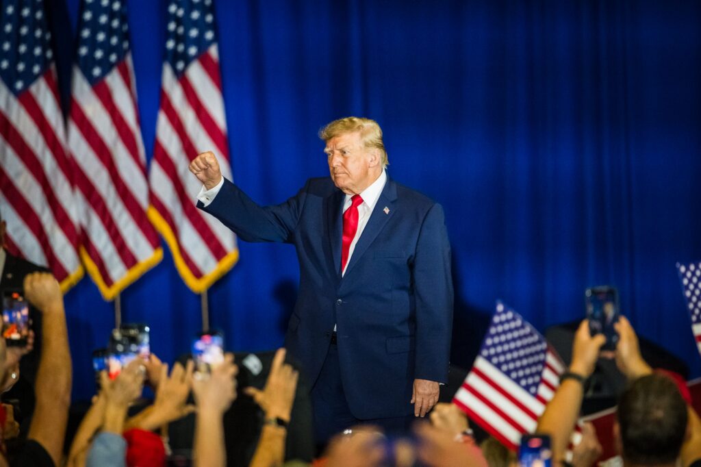 Former President Trump raises his fist in front of a crowd, with American flags in t — Trump midterm election interference