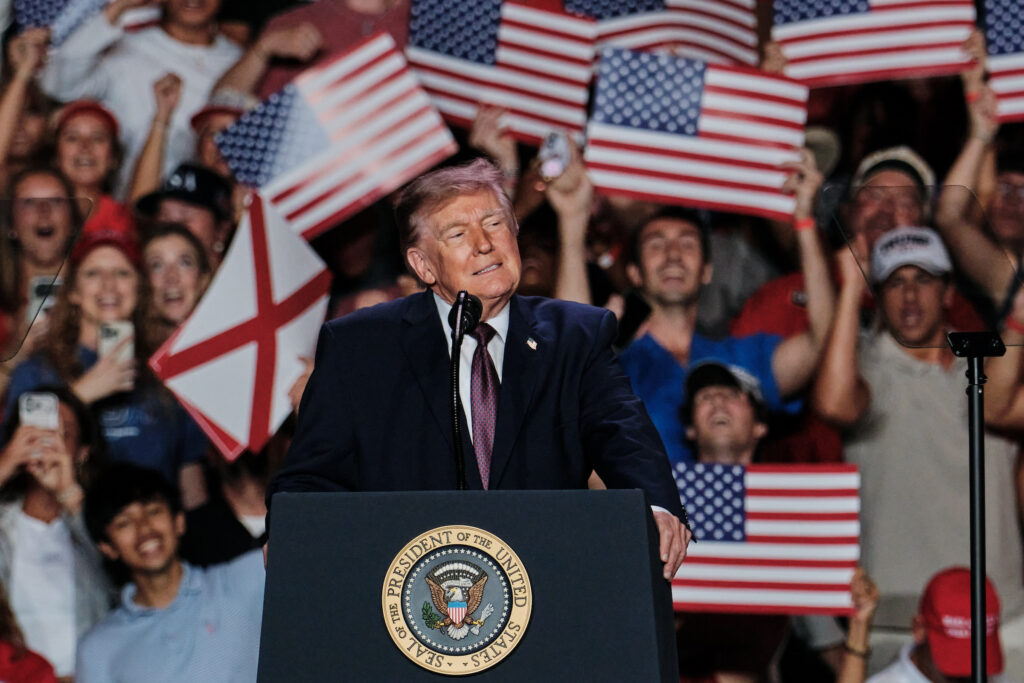 Donald Trump speaking at a rally with supporters holding American flags in the background, highligh — Trump mail-in voting