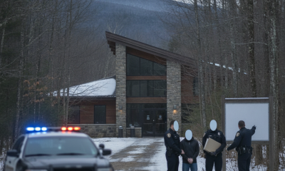 Vermont State Police Shaftsbury Barracks officers stand beside a patrol vehicle and three people outside a stone building.