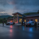 Vermont State Police Shaftsbury Barracks building at dusk, with two police cars and officers outside.